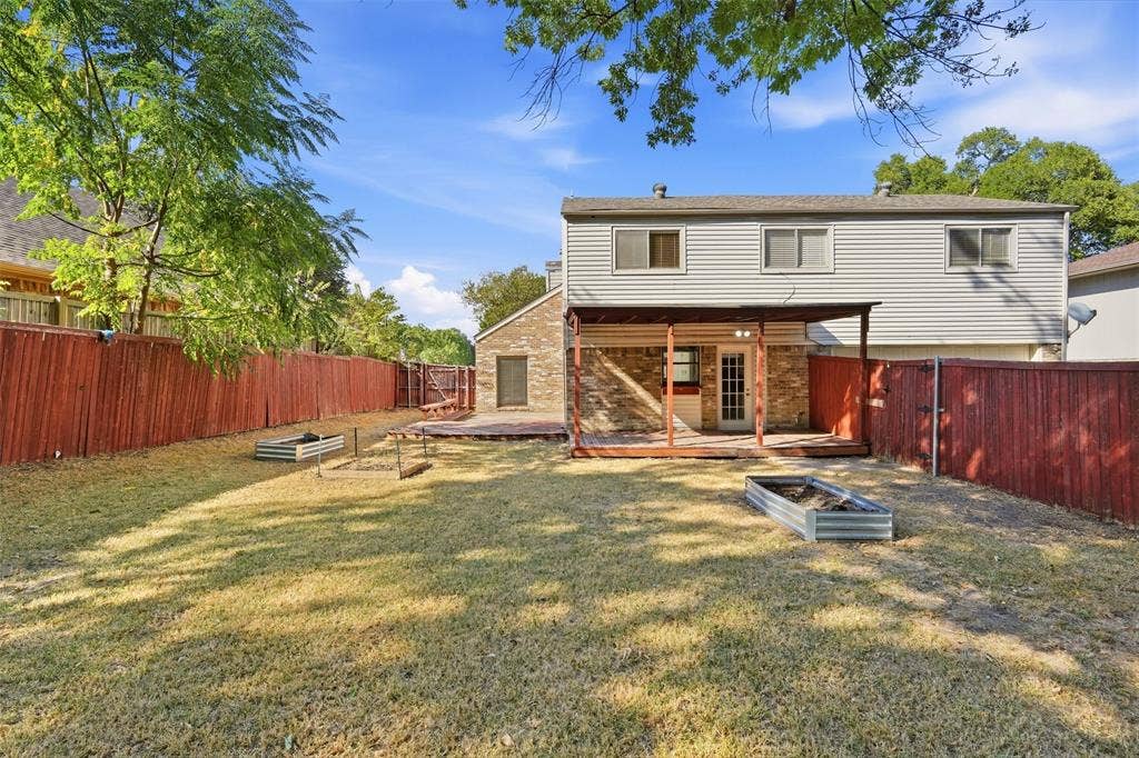 1512 Woodcreek Drive, Richardson, TX 75082 Expansive backyard featuring a covered patio, wood deck, and perimeter fencing