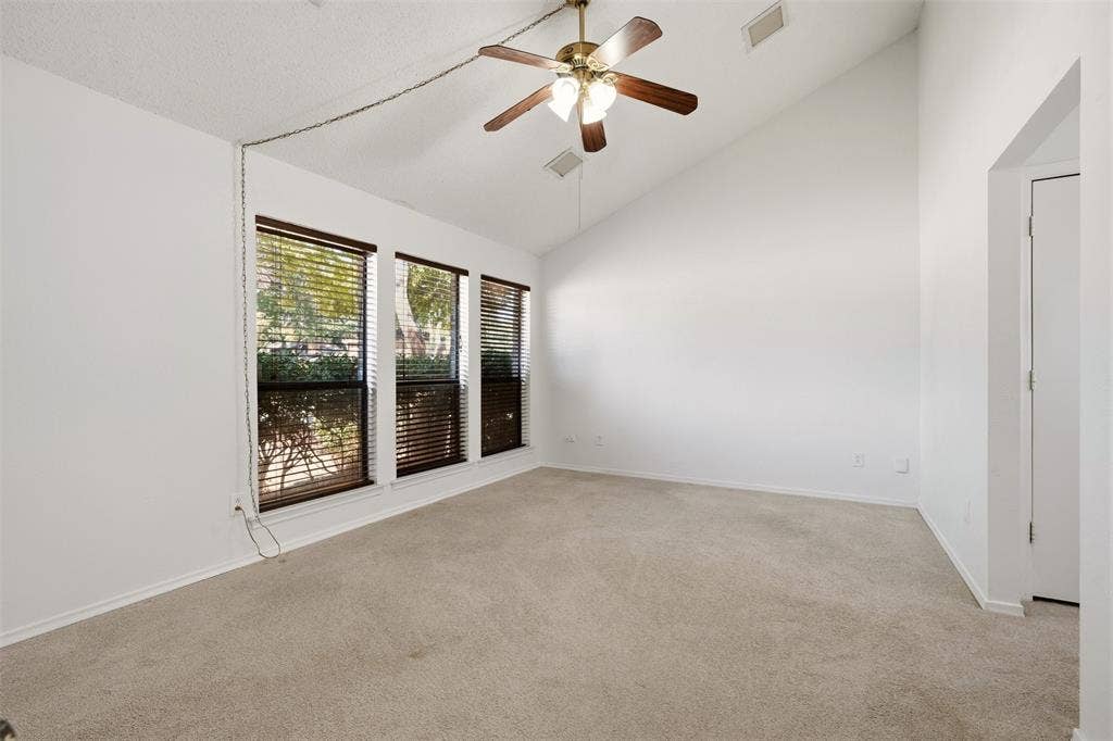 1512 Woodcreek Drive, Richardson, TX 75082 Vaulted ceiling, ceiling fan, three windows with blinds, light-colored carpet, and white walls
