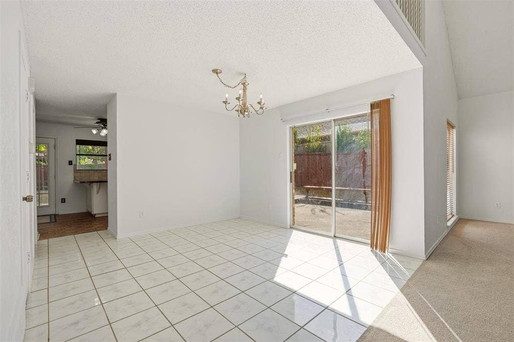 1512 Woodcreek Drive, Richardson, TX 75082 White tile flooring, sliding glass door, overhead chandelier, vaulted ceiling, and built-in shelving