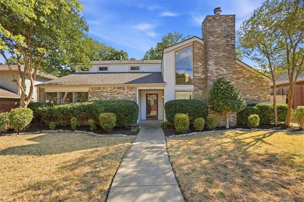 1512 Woodcreek Drive, Richardson, TX 75082 Multi-level residence featuring a brick facade and siding, with a prominent brick chimney