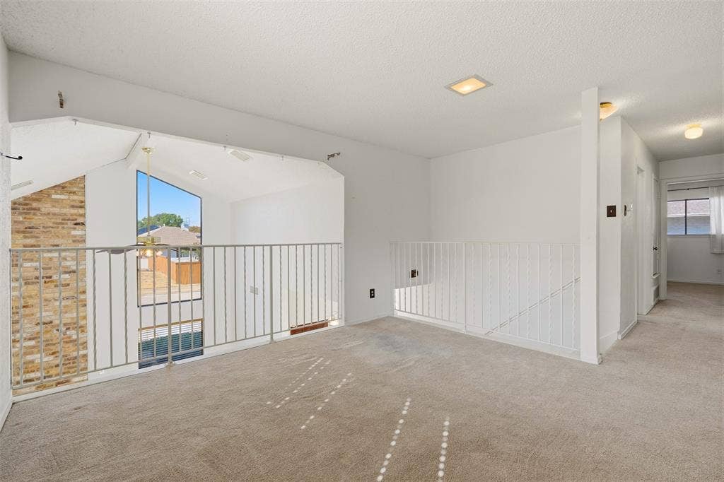 1512 Woodcreek Drive, Richardson, TX 75082 Vaulted ceiling with an expansive window, exposed brick accent wall, and recessed lighting