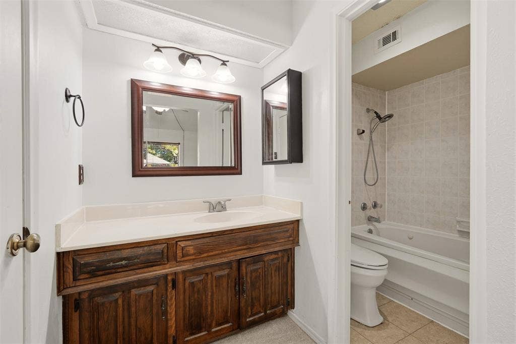 1512 Woodcreek Drive, Richardson, TX 75082 Wood-finish vanity with a single basin sink and light-toned countertop