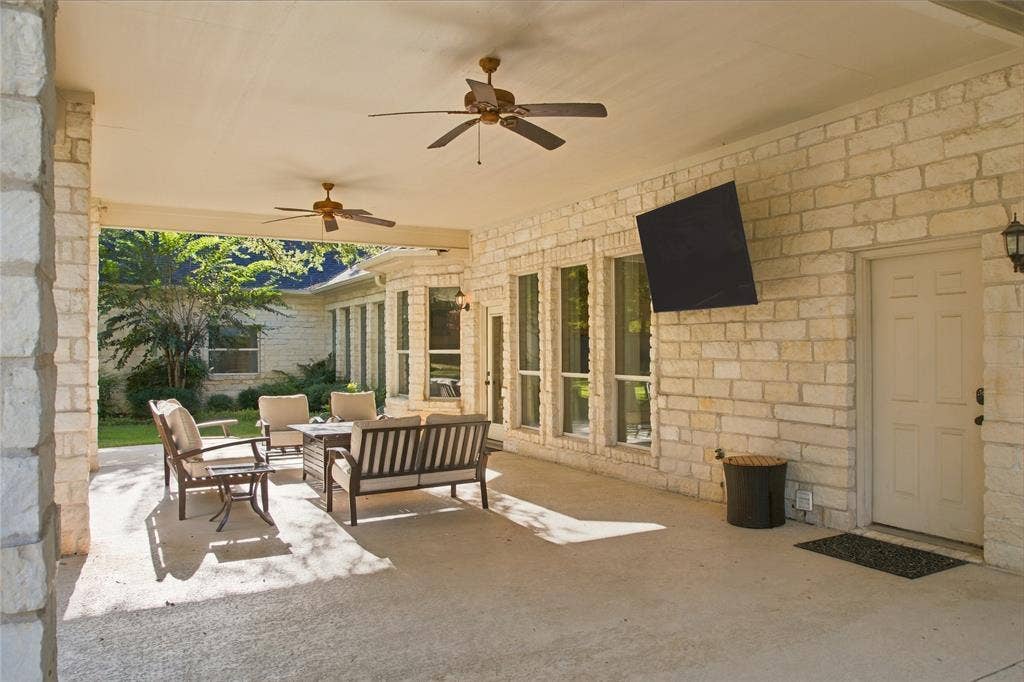 11408 Somerville Drive, Temple, TX 76502 Expansive covered patio featuring a concrete surface, stone exterior walls, and ceiling fans