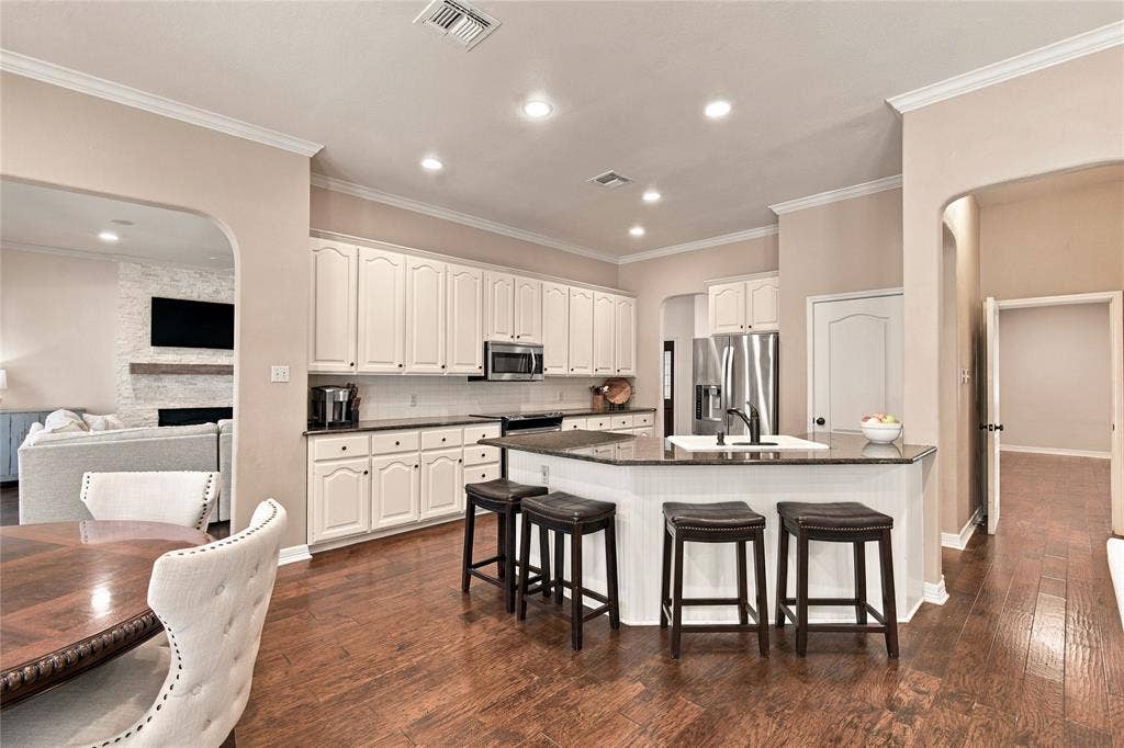 11408 Somerville Drive, Temple, TX 76502 Kitchen featuring a central island with a built-in sink, white cabinetry, dark countertops, recessed lighting, and wood-finish flooring