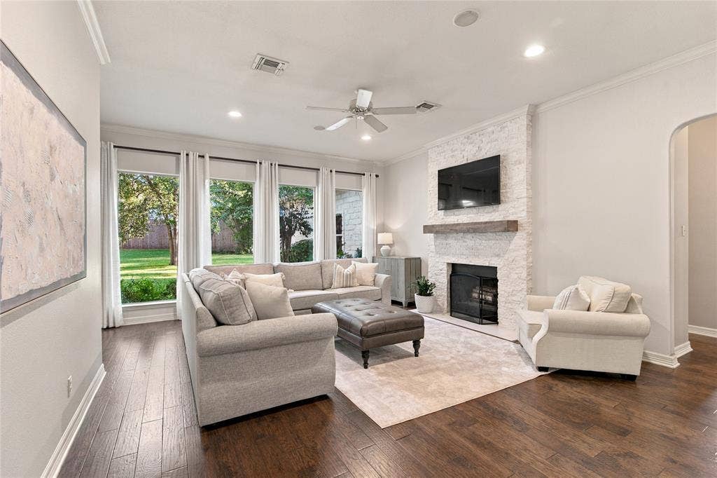 11408 Somerville Drive, Temple, TX 76502 Expansive living area featuring rich wood-finish flooring, a white brick-clad fireplace with a substantial wood mantel, a ceiling fan, recessed lighting, and multiple windows overlooking greenery