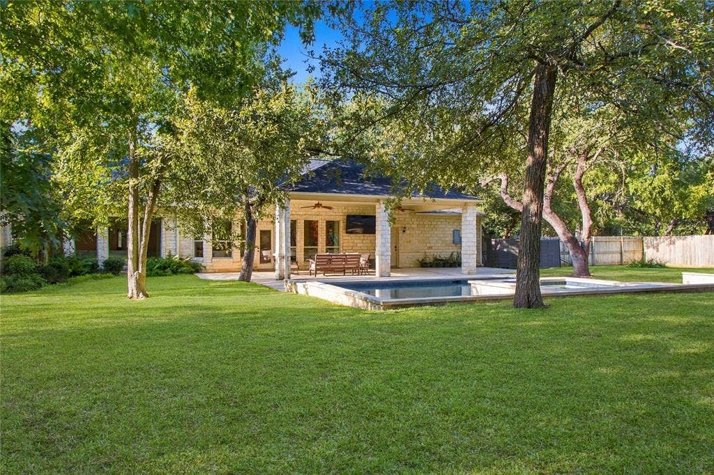 11408 Somerville Drive, Temple, TX 76502 Expansive green lawn with mature trees, stone exterior, covered patio, and in-ground swimming pool