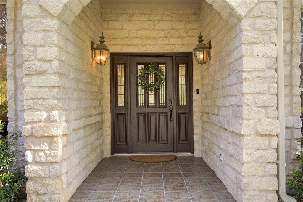 11408 Somerville Drive, Temple, TX 76502 Stone exterior with a double entry door featuring sidelights, overhead transom windows, and wall-mounted exterior light fixtures