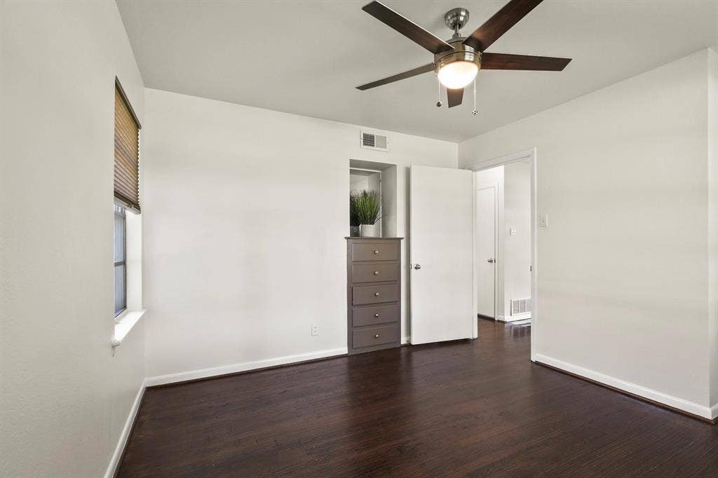 Wood-finish flooring, ceiling fan with integrated lighting, white walls, and white trim