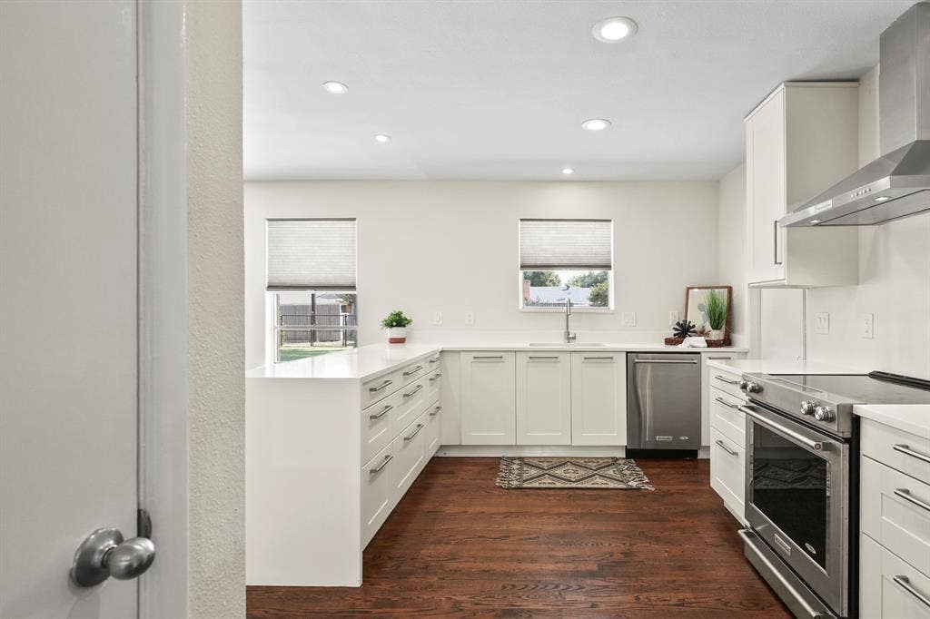 Modern kitchen featuring recessed lighting, white cabinetry, stainless steel appliances, white countertops, and wood-finish flooring