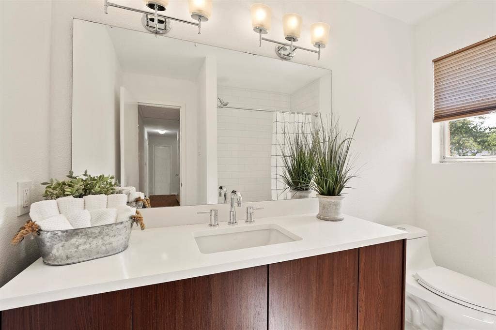 White vanity with an integrated rectangular sink, chrome faucet, and wood-finish cabinetry