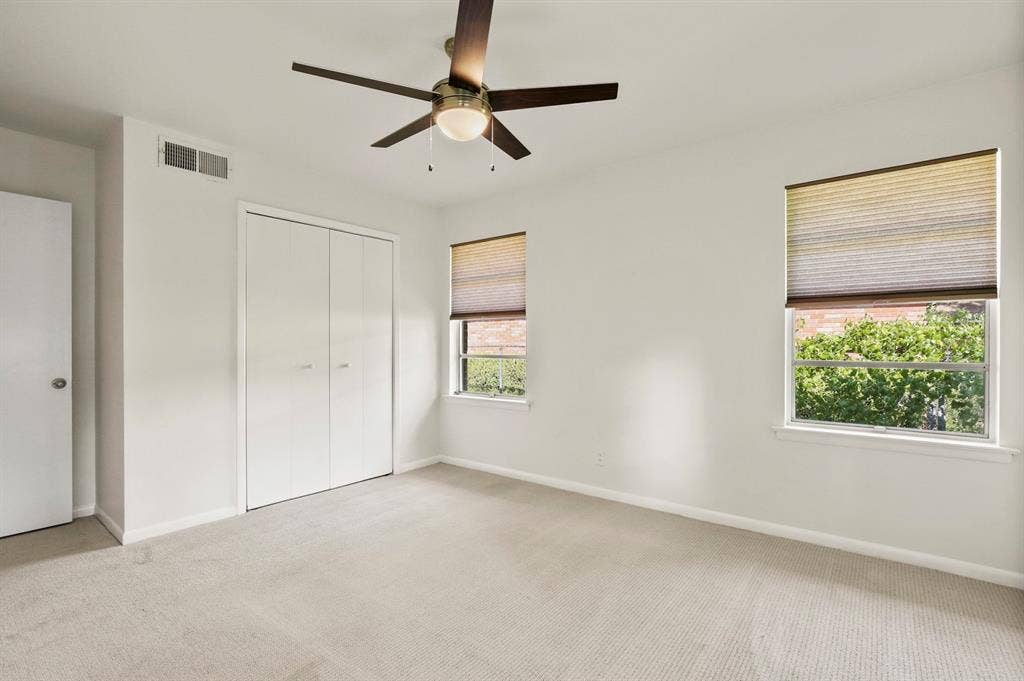 Recessed lighting, wood-finish ceiling fan, two windows with blinds, and built-in closet with bifold doors