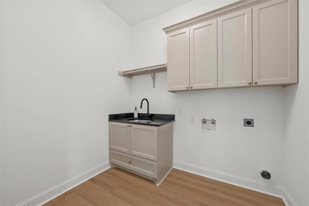 20 N Ritchie Road, Woodway, TX 76712 Laundry area featuring wood-finish flooring, built-in cabinetry, a utility sink with a matte black faucet, and a wall-mounted shelving unit