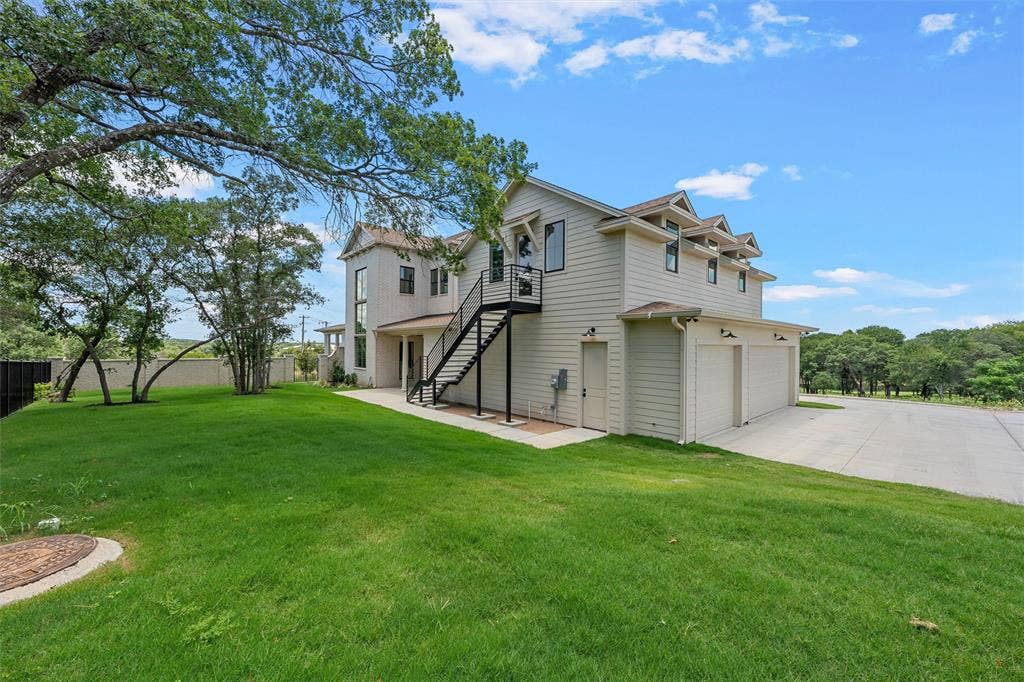20 N Ritchie Road, Woodway, TX 76712 Two-story residence with light-colored siding, a multi-car garage, and an exterior staircase with a black railing