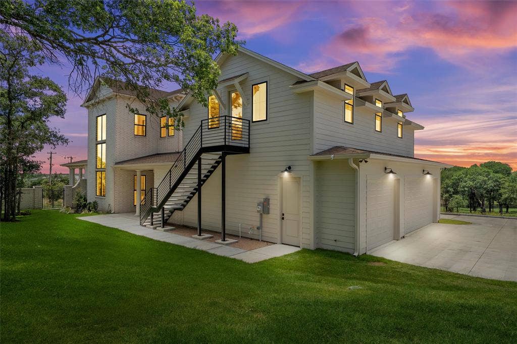 20 N Ritchie Road, Woodway, TX 76712 White siding exterior with multiple dormer windows, a three-car garage, and an external metal staircase with railing