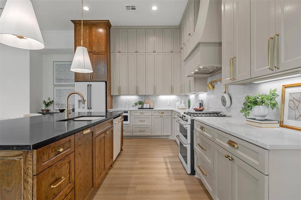 20 N Ritchie Road, Woodway, TX 76712 Gourmet kitchen with wood-finish flooring, two-tone cabinetry, stone countertops, and a full suite of stainless steel appliances