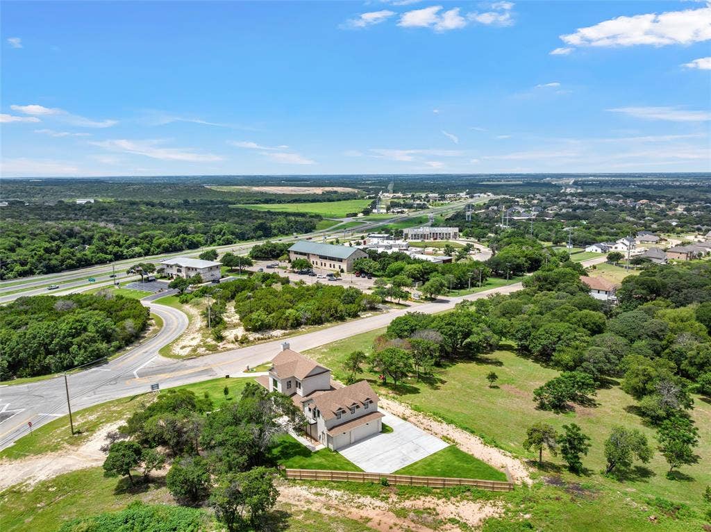 20 N Ritchie Road, Woodway, TX 76712 Aerial perspective showcasing a property with a light-colored exterior and multi-gabled roof, featuring a concrete driveway and a fenced perimeter