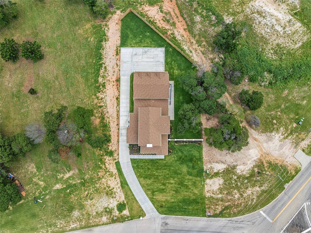 20 N Ritchie Road, Woodway, TX 76712 Expansive parcel featuring a newly constructed residence with a brown shingle roof, a concrete driveway, and established green lawns