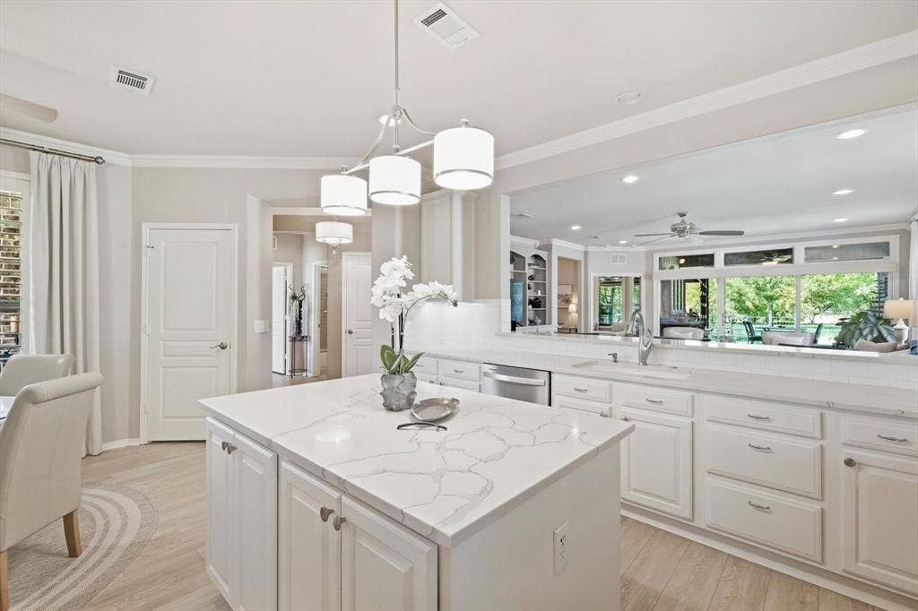 1641 Overwood Drive, Frisco, TX 75036 Bright, open kitchen featuring a large center island with white cabinetry, white quartz countertops, stainless steel appliances, pendant lighting, and abundant natural light from expansive windows