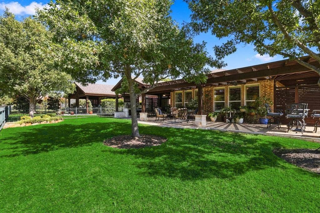 1641 Overwood Drive, Frisco, TX 75036 Expansive green lawn, mature trees providing natural shade, paver stone patio with a wood pergola, brick exterior, and multiple large windows