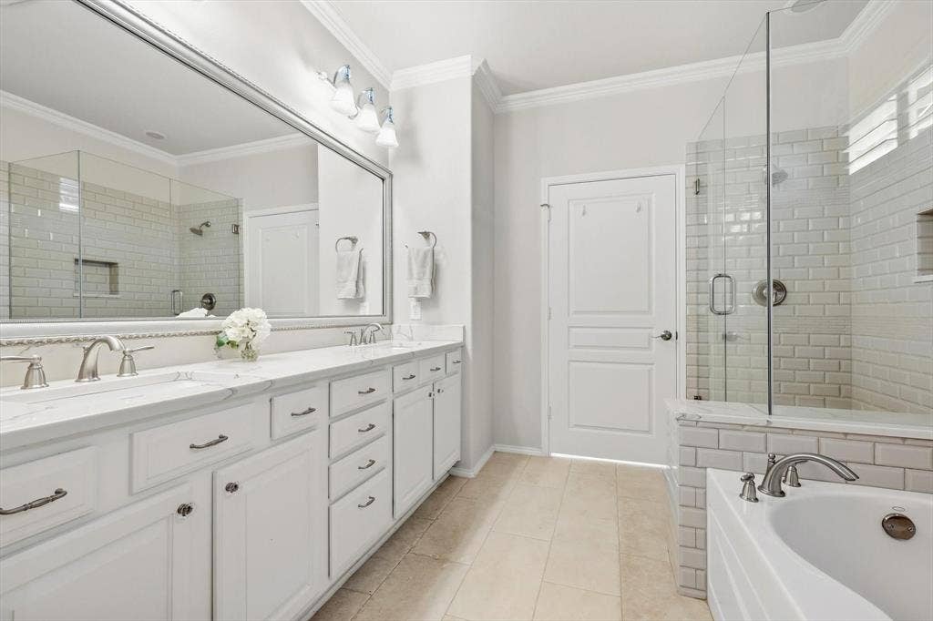 1641 Overwood Drive, Frisco, TX 75036 Dual vanity with undermount sinks and white shaker-style cabinetry, a spacious mirror, a glass-enclosed shower with subway tile, and a built-in tub