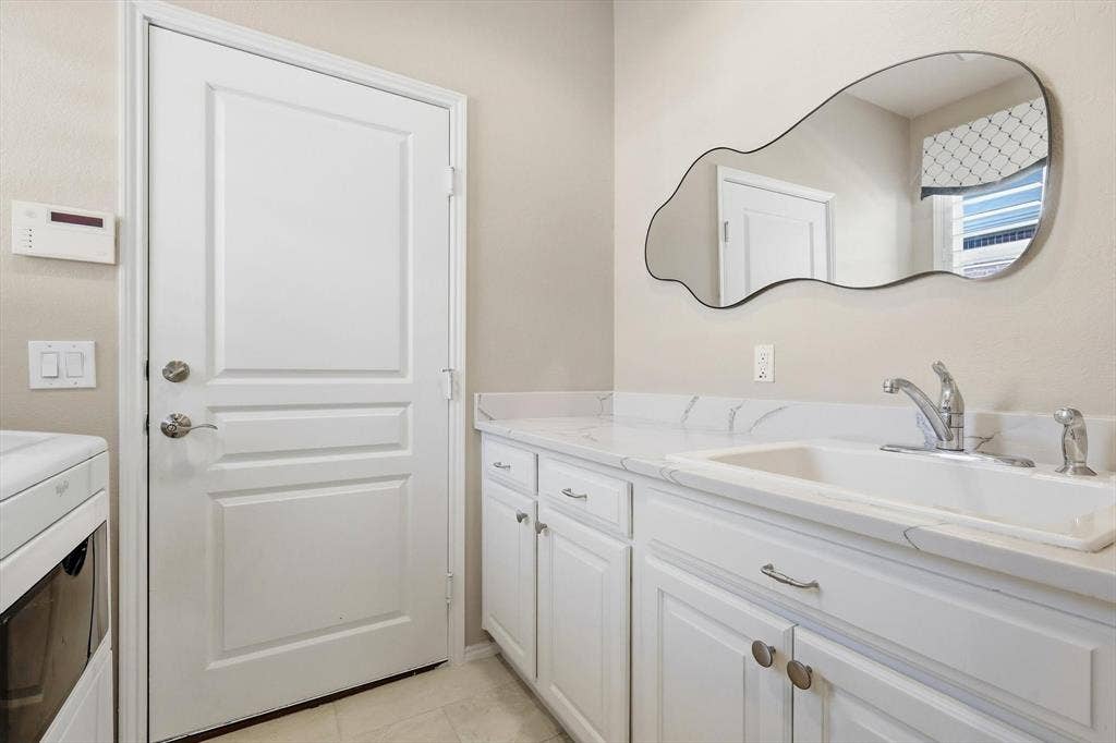 1641 Overwood Drive, Frisco, TX 75036 White shaker-style cabinetry with chrome hardware, an integrated sink, and a stone-finish countertop