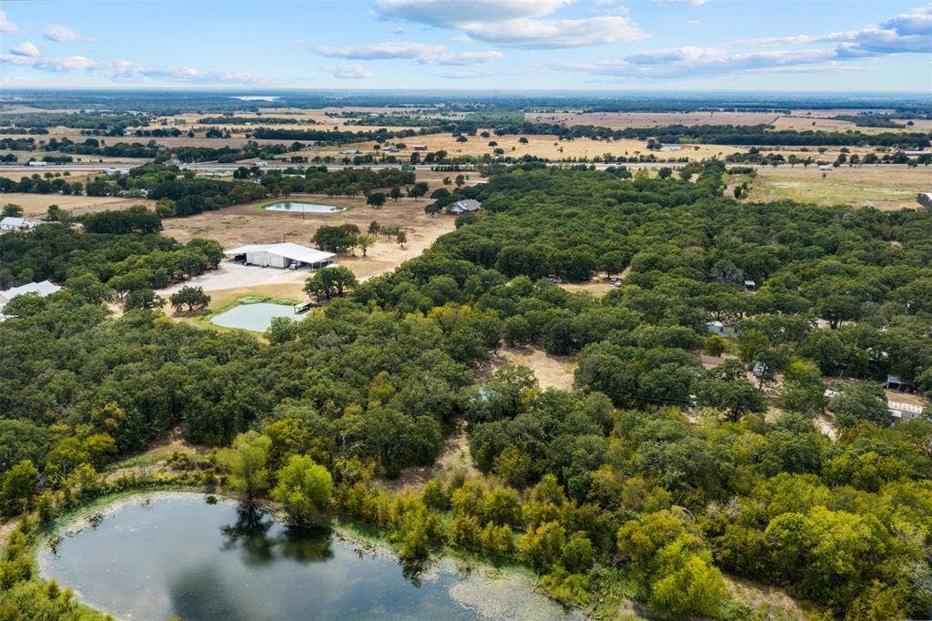 172 M Burton Street, Riesel, TX 76682 Expansive property featuring dense tree coverage, multiple ponds, and a large outbuilding