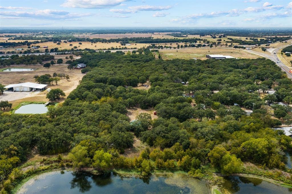 172 M Burton Street, Riesel, TX 76682 Expansive property featuring mature tree coverage, multiple water features, and a large metal outbuilding