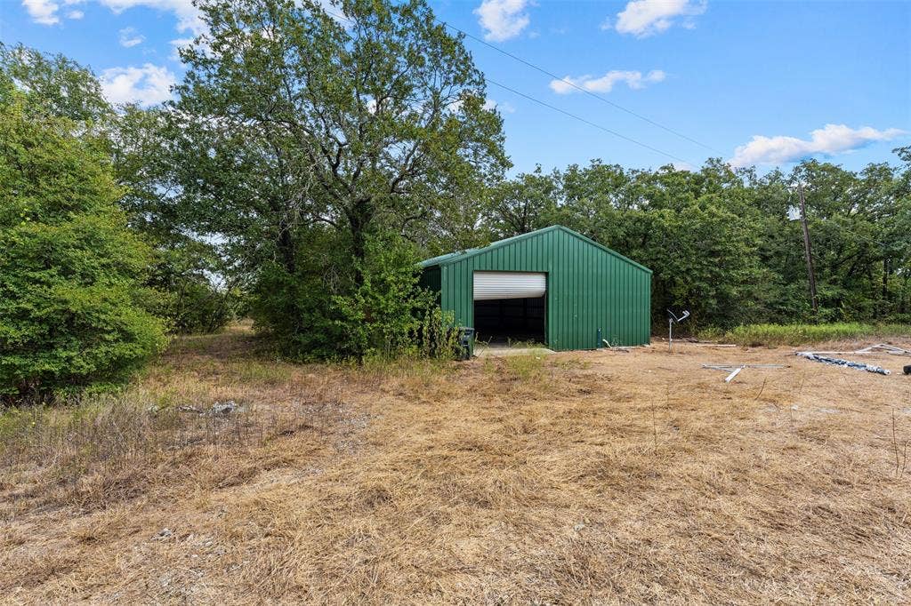 172 M Burton Street, Riesel, TX 76682 Green metal-sided utility building with a roll-up door