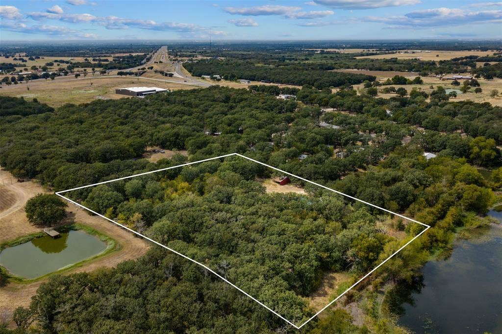 172 M Burton Street, Riesel, TX 76682 Wooded acreage featuring a red structure and a water body along the property perimeter