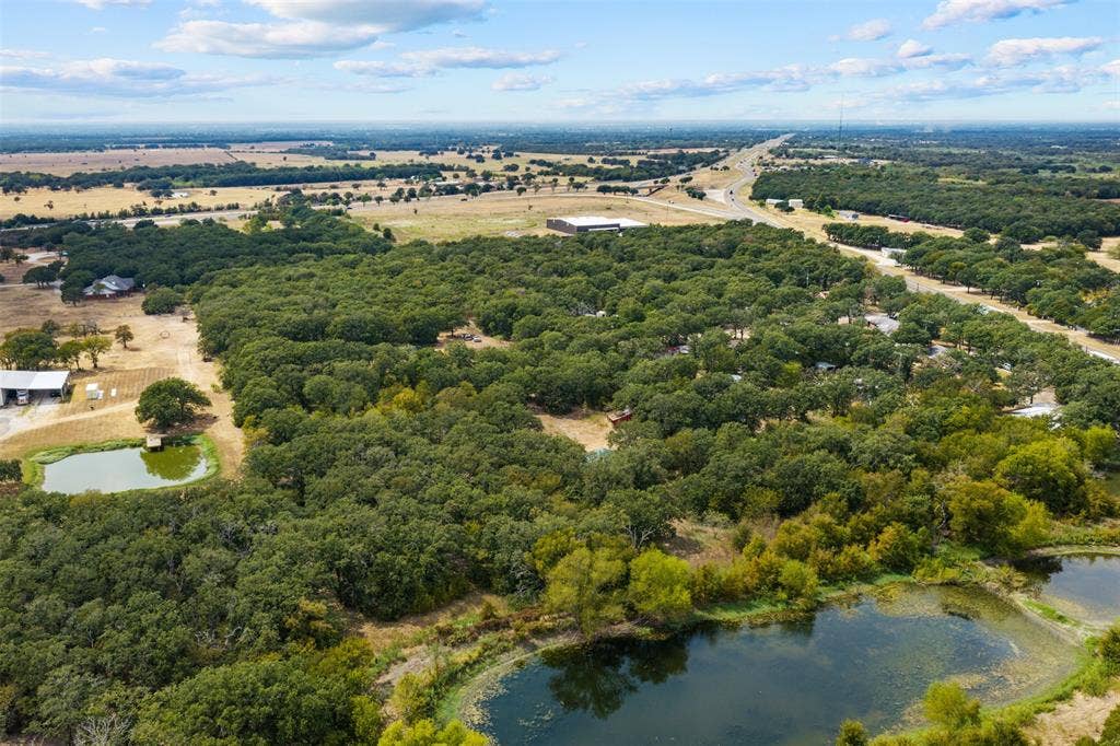 172 M Burton Street, Riesel, TX 76682 Expansive land parcel featuring dense tree coverage, multiple water features, and a distant highway access