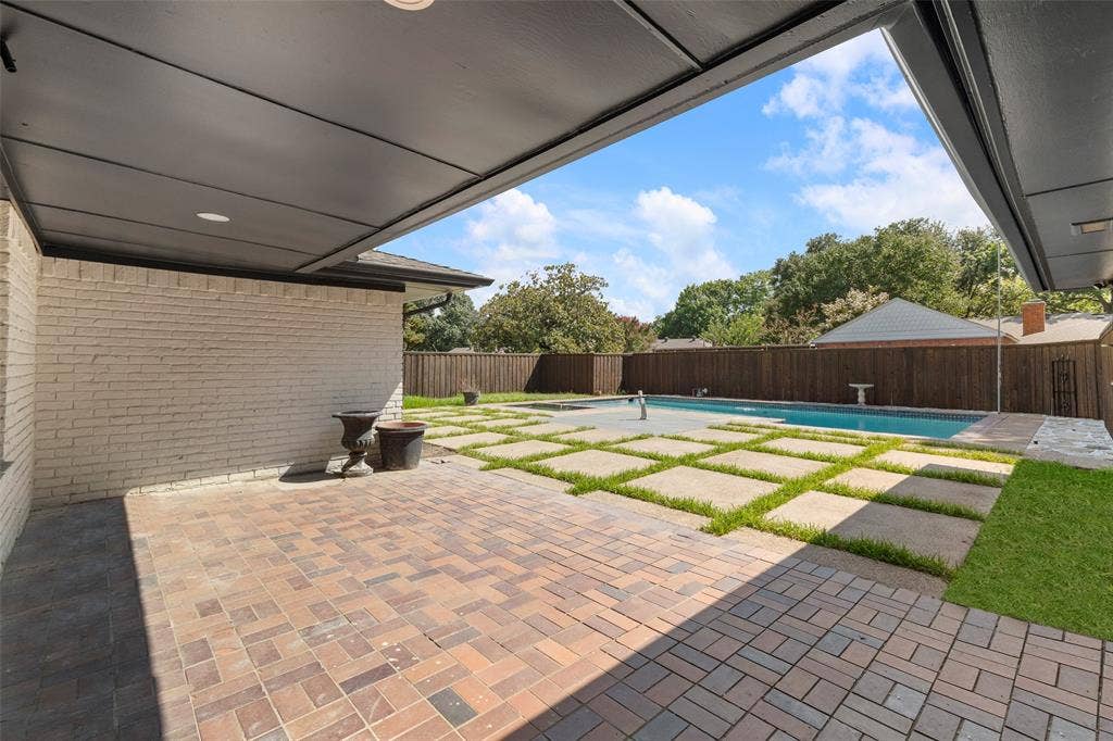 1612 Northcrest Drive, Plano, TX 75075 Covered outdoor patio with paver flooring, white brick exterior, mature privacy fencing, concrete stepping stones, and a rectangular swimming pool
