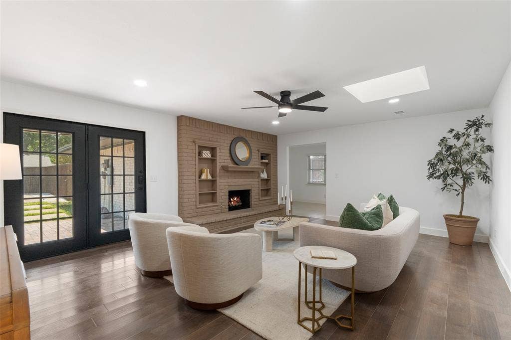 1612 Northcrest Drive, Plano, TX 75075 Brick fireplace with built-in shelving, wood-finish flooring, recessed lighting, ceiling fan, and French doors