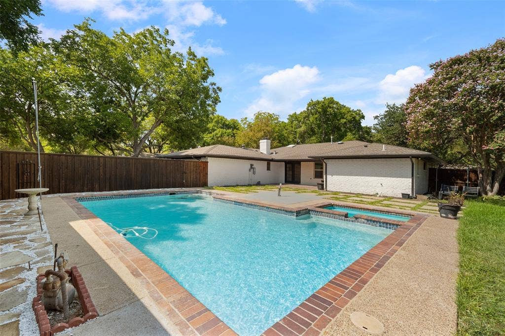 1612 Northcrest Drive, Plano, TX 75075 Backyard features an in-ground swimming pool with an integrated spa, brick coping, and a surrounding concrete deck