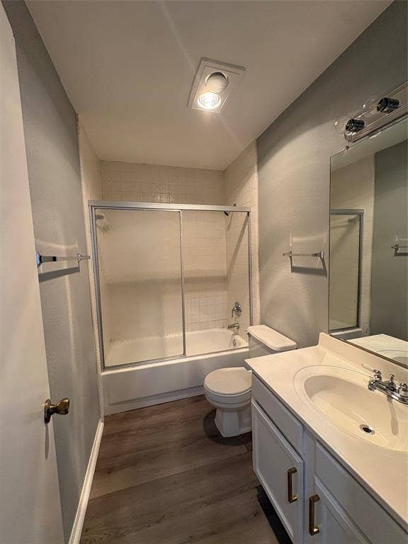 1120 Old Barn Lane, Mesquite, TX 75149 Bathroom featuring wood-finish flooring, white vanity with gold-tone hardware, integrated sink, and a shower-tub combination with sliding glass doors