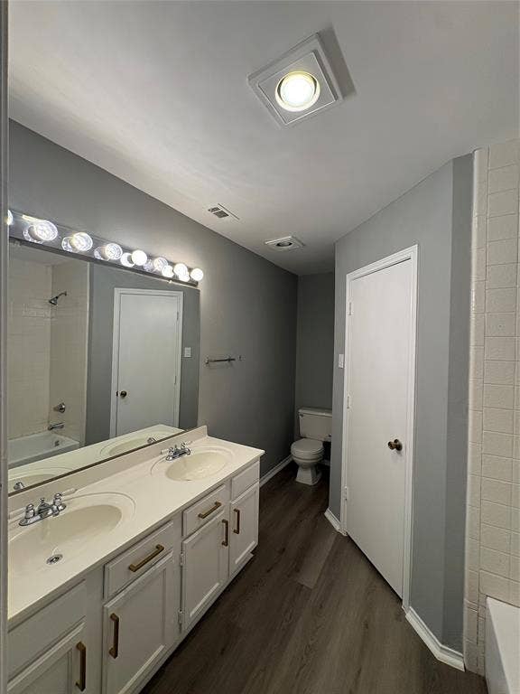 1120 Old Barn Lane, Mesquite, TX 75149 Dual vanity with integrated sinks, wood-finish flooring, and white cabinetry with brass-toned hardware