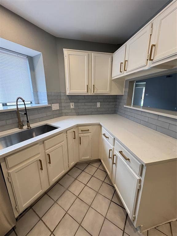 1120 Old Barn Lane, Mesquite, TX 75149 White cabinetry with gold-tone hardware, light-toned countertops, subway tile backsplash, stainless steel sink, and gray tiled flooring