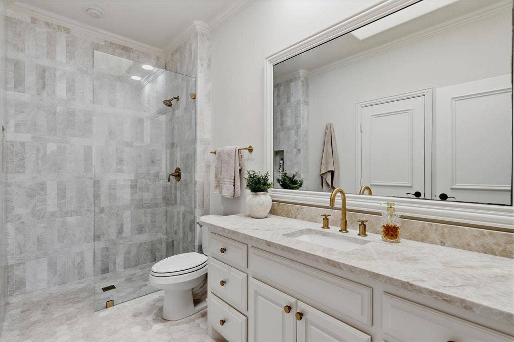 Marble tile, quartzite surfaces and polished brass fixtures elevate this remodeled ensuite bath.