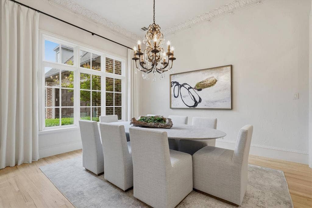 The formal dining room is filled with natural light and detailed with elegant millwork and a statement chandelier.