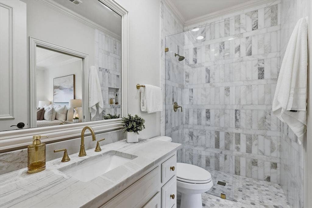 The updated ensuite bath features marble finishes, a glass-enclosed shower and elegant brass fixtures.