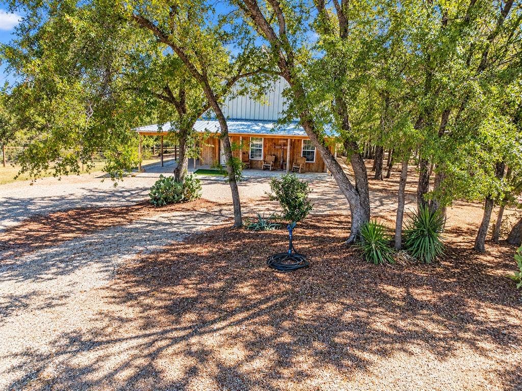 7245 County Road 4095, Kaufman, TX 75142 Gravel driveway leading to a residence with a metal roof and full-length covered porch