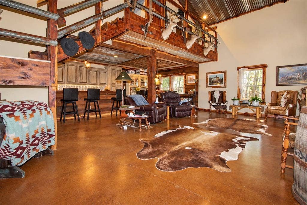 7245 County Road 4095, Kaufman, TX 75142 Vaulted corrugated metal ceiling, exposed wood beams, stained concrete flooring, built-in bar with cabinetry, and wood-framed windows