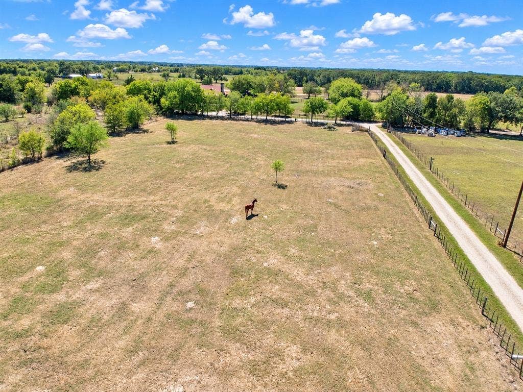 7245 County Road 4095, Kaufman, TX 75142 Expansive open field with scattered trees and a winding unpaved road