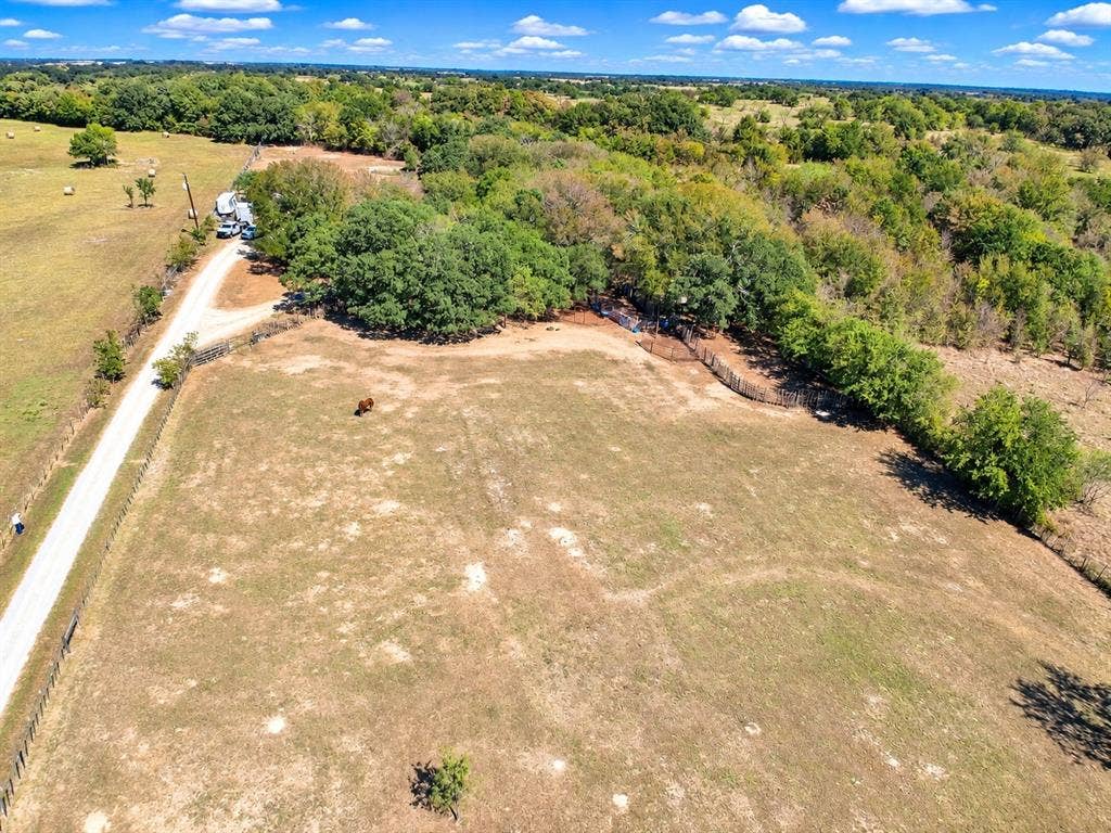 7245 County Road 4095, Kaufman, TX 75142 Expansive rural property featuring an unpaved road, mature trees, and a spacious open field
