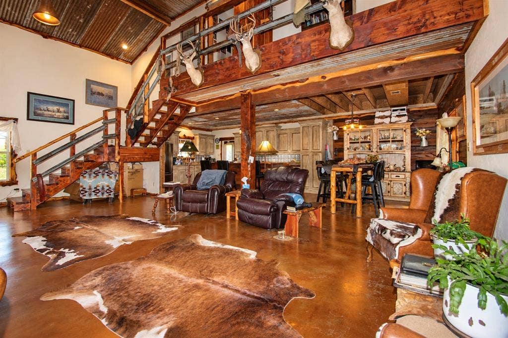 7245 County Road 4095, Kaufman, TX 75142 Open-concept living space featuring a high vaulted ceiling with corrugated metal and wood beam accents