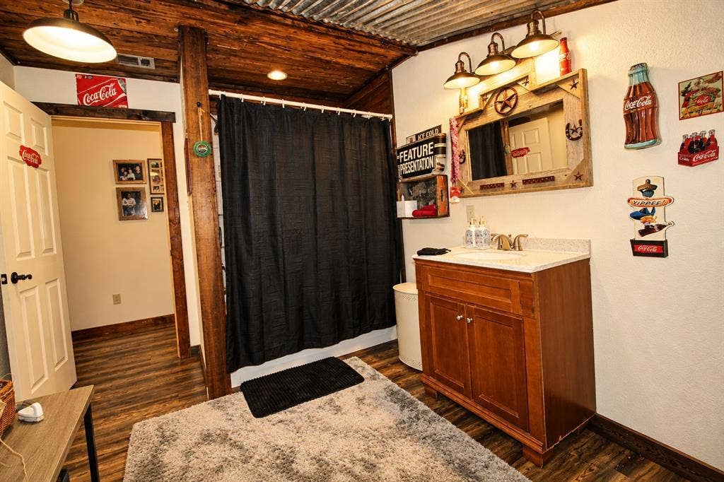7245 County Road 4095, Kaufman, TX 75142 Wood-finish flooring, corrugated metal ceiling, wood plank ceiling, wood vanity with a stone-finish countertop, and a built-in vanity light fixture