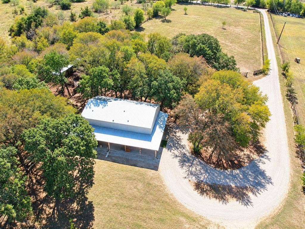 7245 County Road 4095, Kaufman, TX 75142 Expansive property featuring a metal roof structure, a gravel driveway, and mature trees