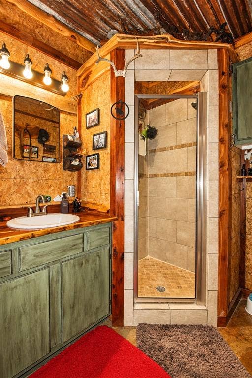 7245 County Road 4095, Kaufman, TX 75142 Wood-finish wall paneling, custom wood vanity with integrated sink, tile-surround shower with glass enclosure, wood-clad ceiling, and overhead vanity lighting