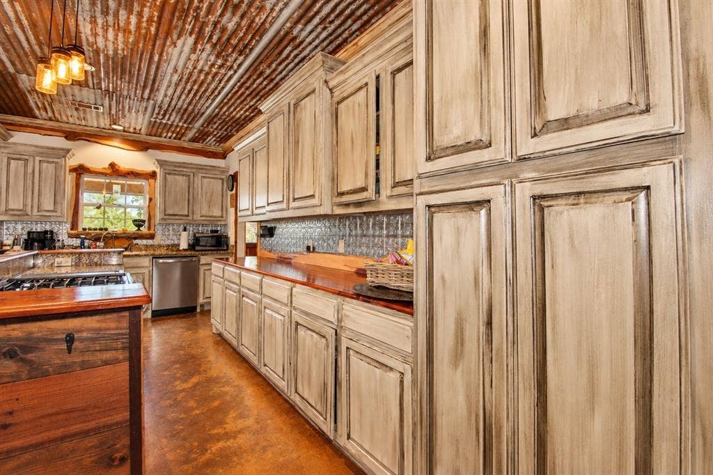 7245 County Road 4095, Kaufman, TX 75142 Corrugated metal ceiling, custom distressed cabinetry, rich wood countertops, stainless steel appliances, and a unique tile backsplash