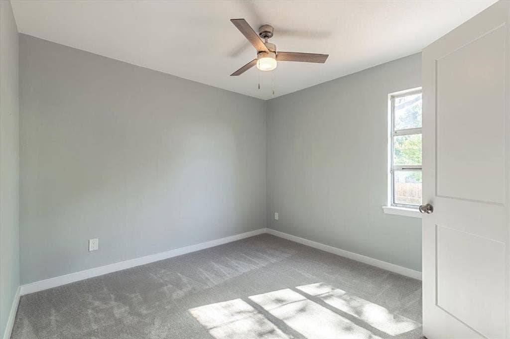 12326 Dandridge Drive, Dallas, TX 75243 Neutral gray wall paint with white trim, gray carpeting, a single window, and a ceiling fan with integrated lighting