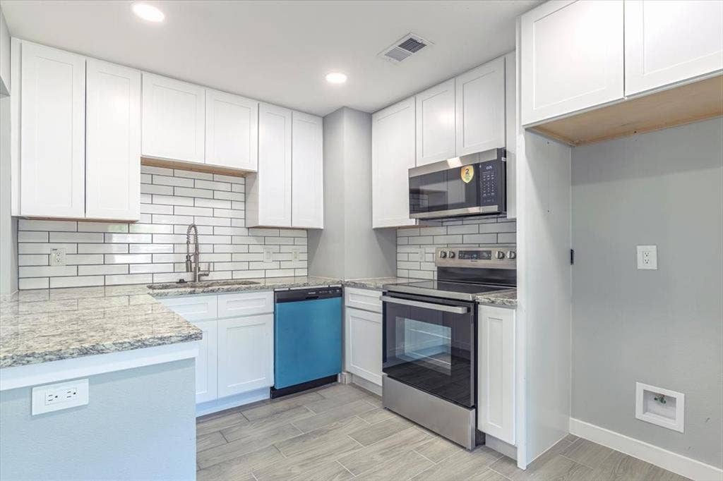 12326 Dandridge Drive, Dallas, TX 75243 White shaker cabinetry, light-toned granite countertops, a subway tile backsplash, and stainless steel appliances